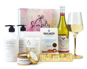 Giftbox with body products, chocolate and a bottle of wine in front
